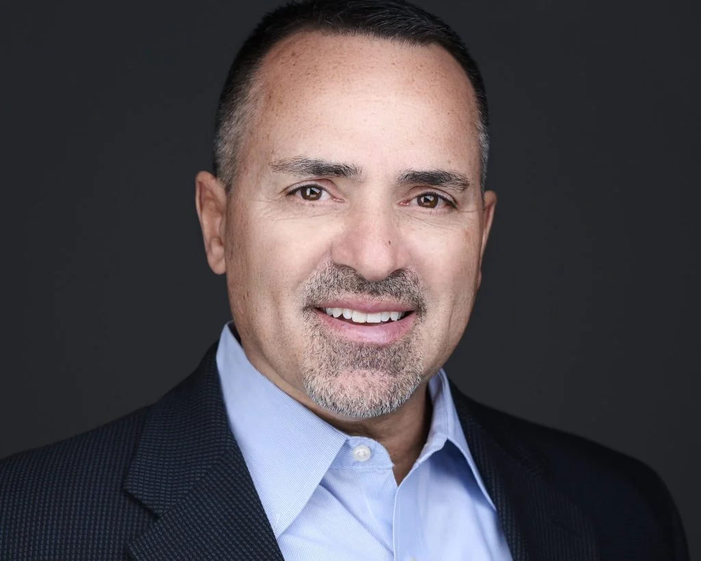 Professional headshot of a man with gray hair in a navy suit